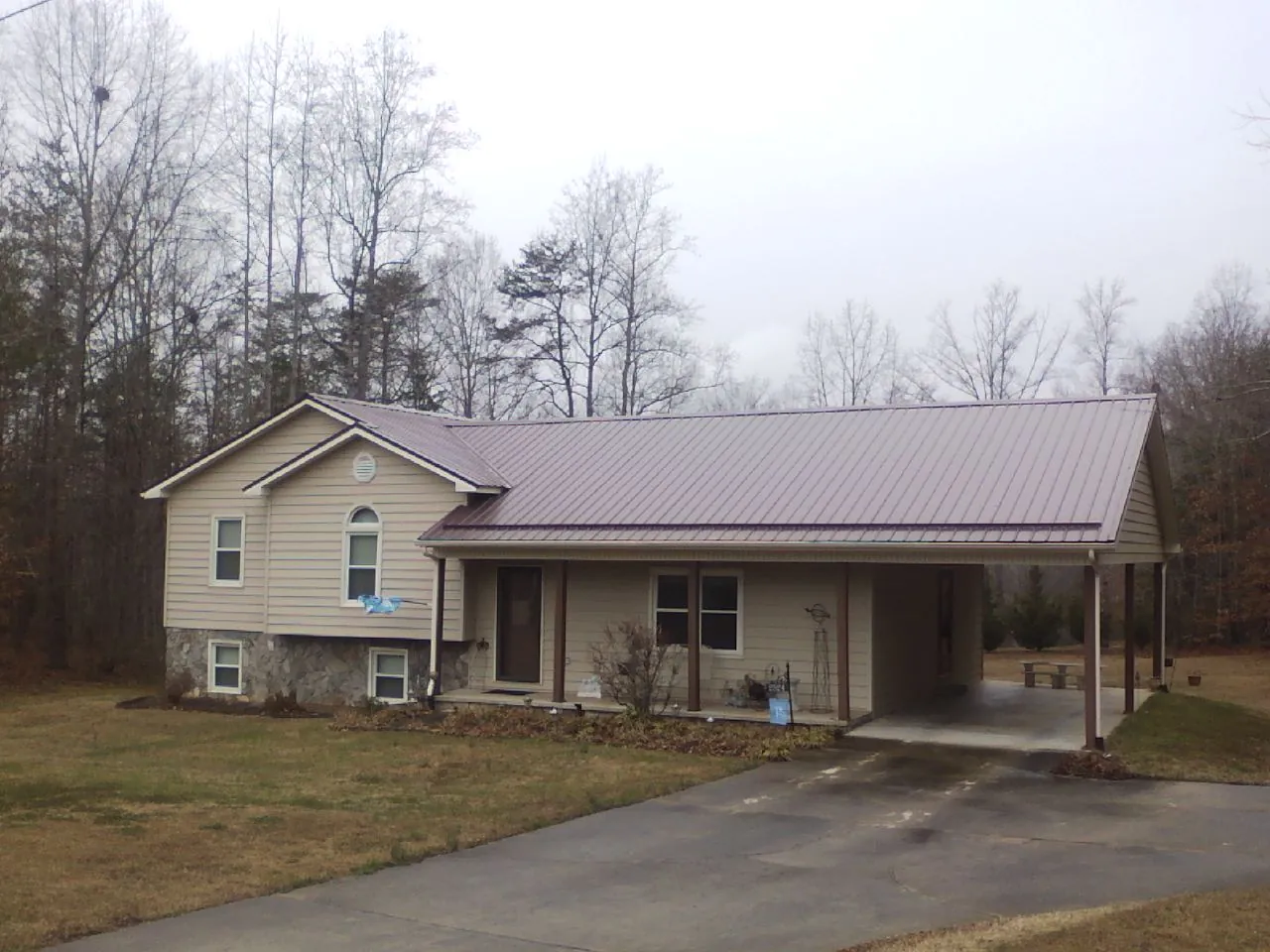 Burgundy metal roof on a tan split level home with an attached carport in Ellis