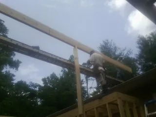 Carpenter setting a ridge beam over a new addition frame — Ice Dam Removal by Roofing Brothers in Ellis