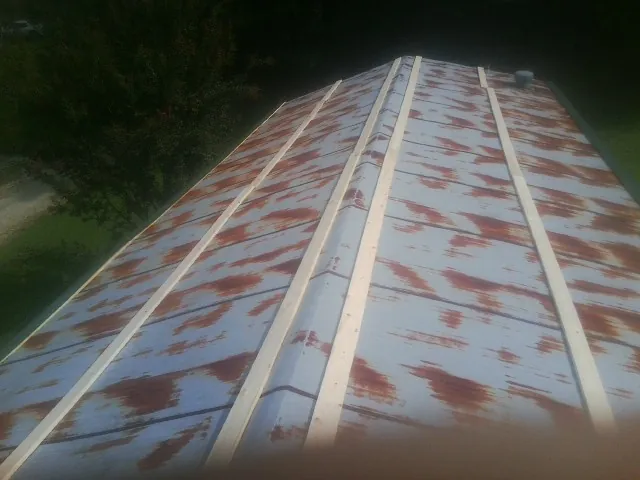 Rusted metal roof panels with new wood purlins before replacement — Storm Damage Roof Repair in Ellis by Roofing Brothers