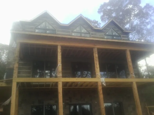 Dormers and porch framing on a large log home under construction — Roof Coating work by our crew in Ellis