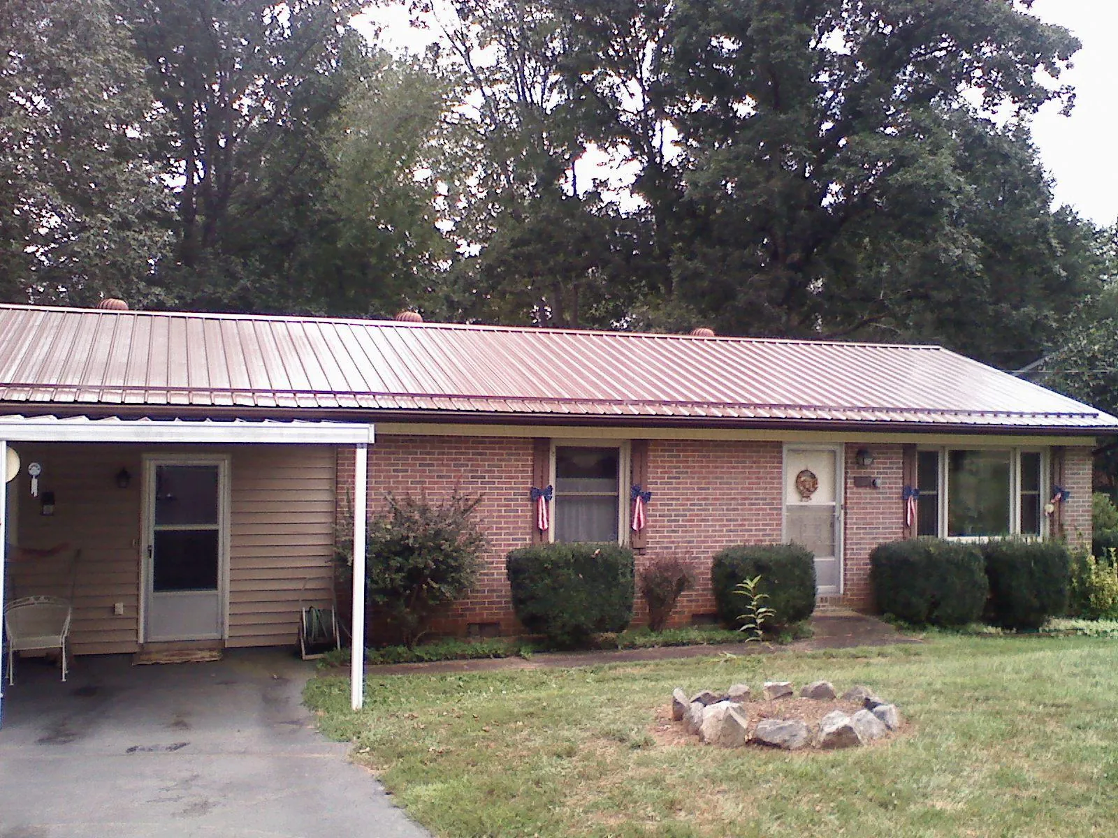 Bronze metal roof and carport on a brick ranch home — Roof Repair work by our crew in Ellis